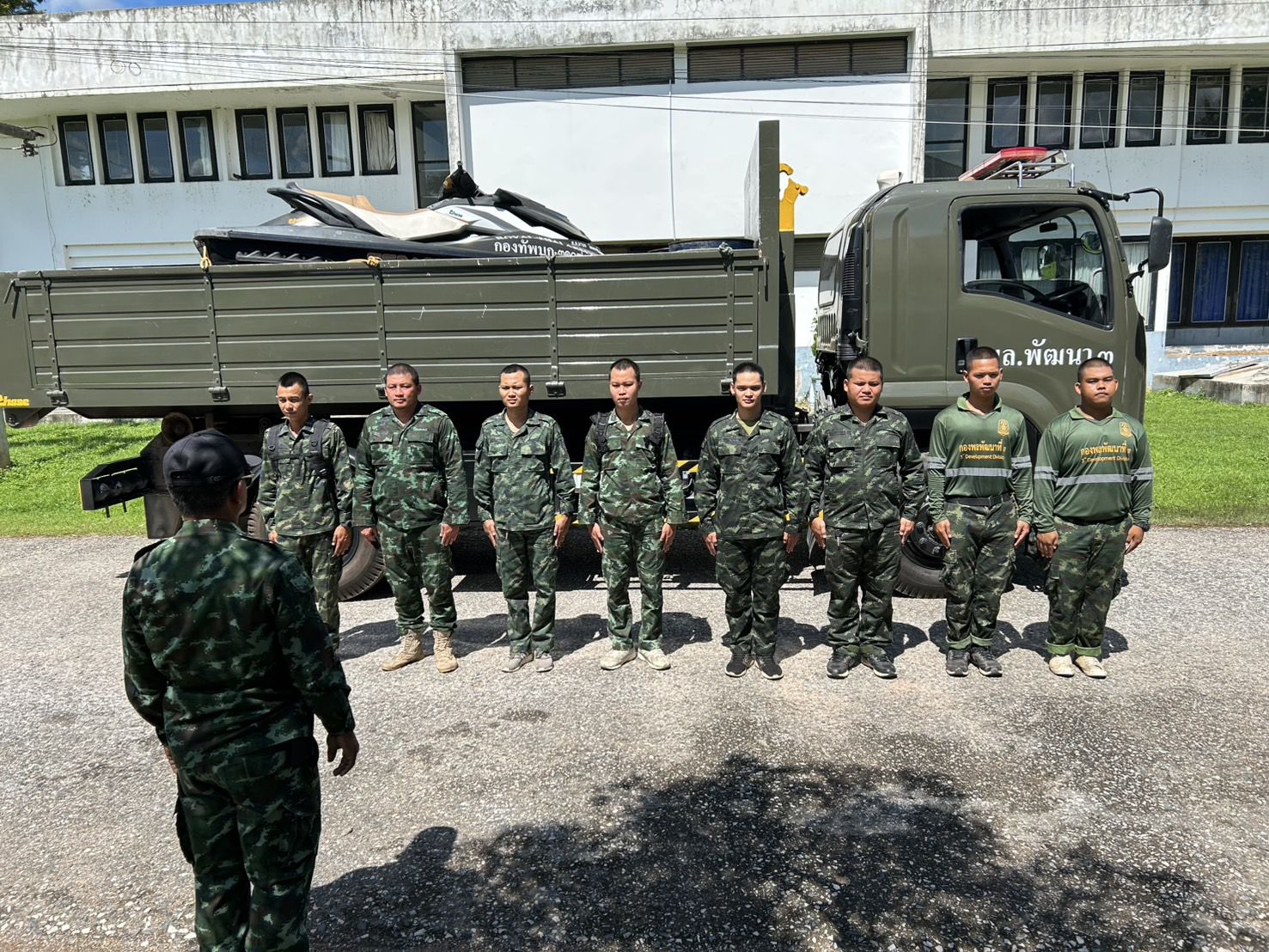 a group of men in uniform standing in front of a truck